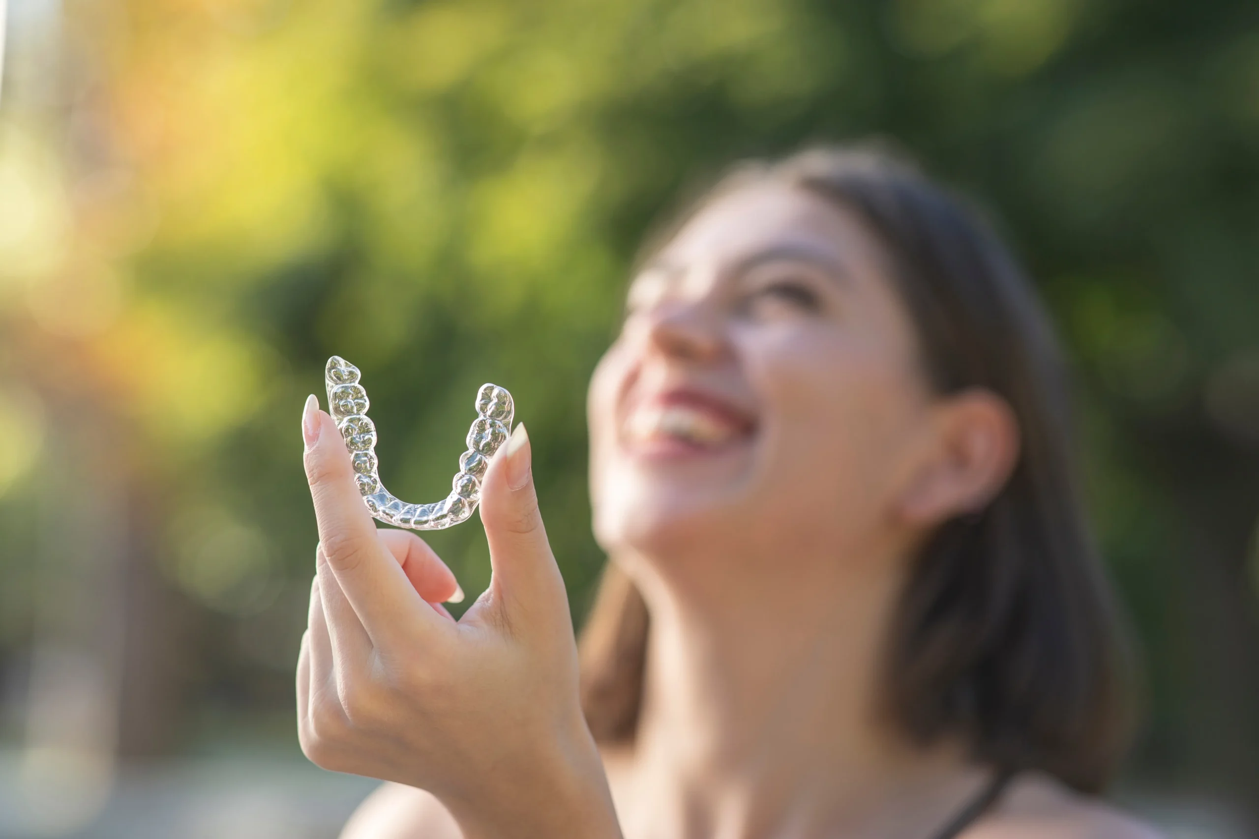 woman smiling and holding an invisalign